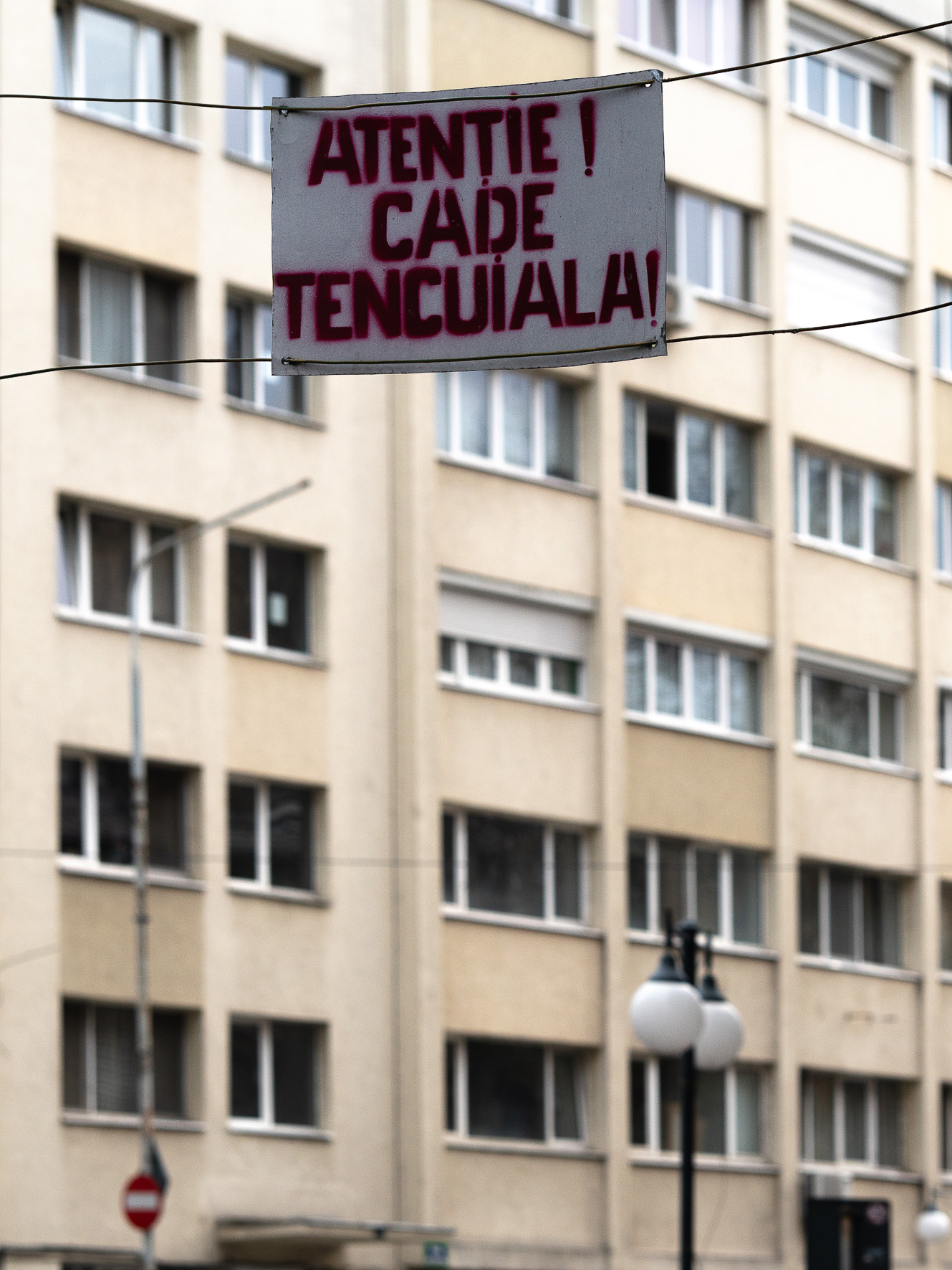 Warning sign suspended between residential buildings in Bucharest