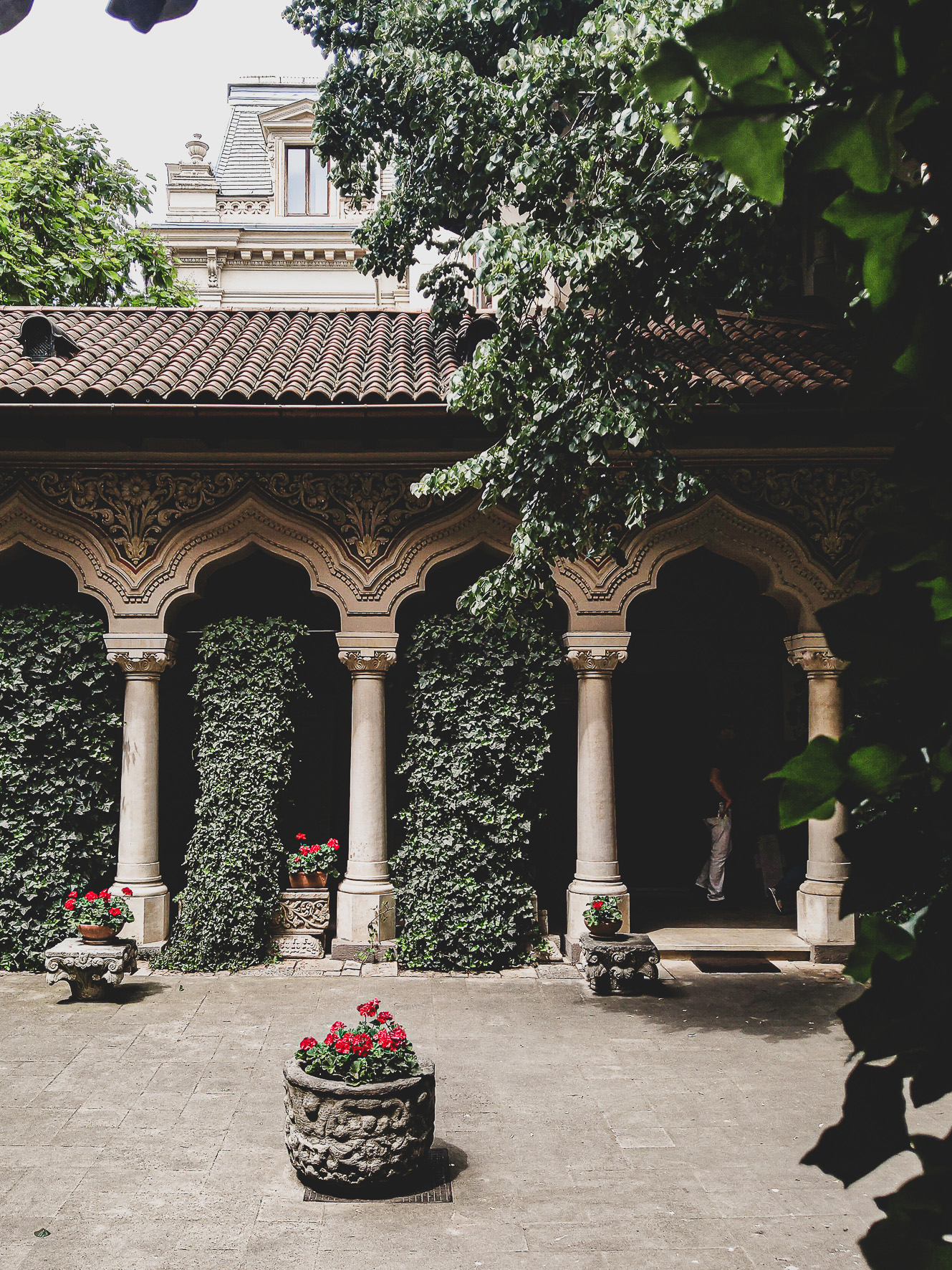 Stavropoleos courtyard framed by arches, foliage and red flowers