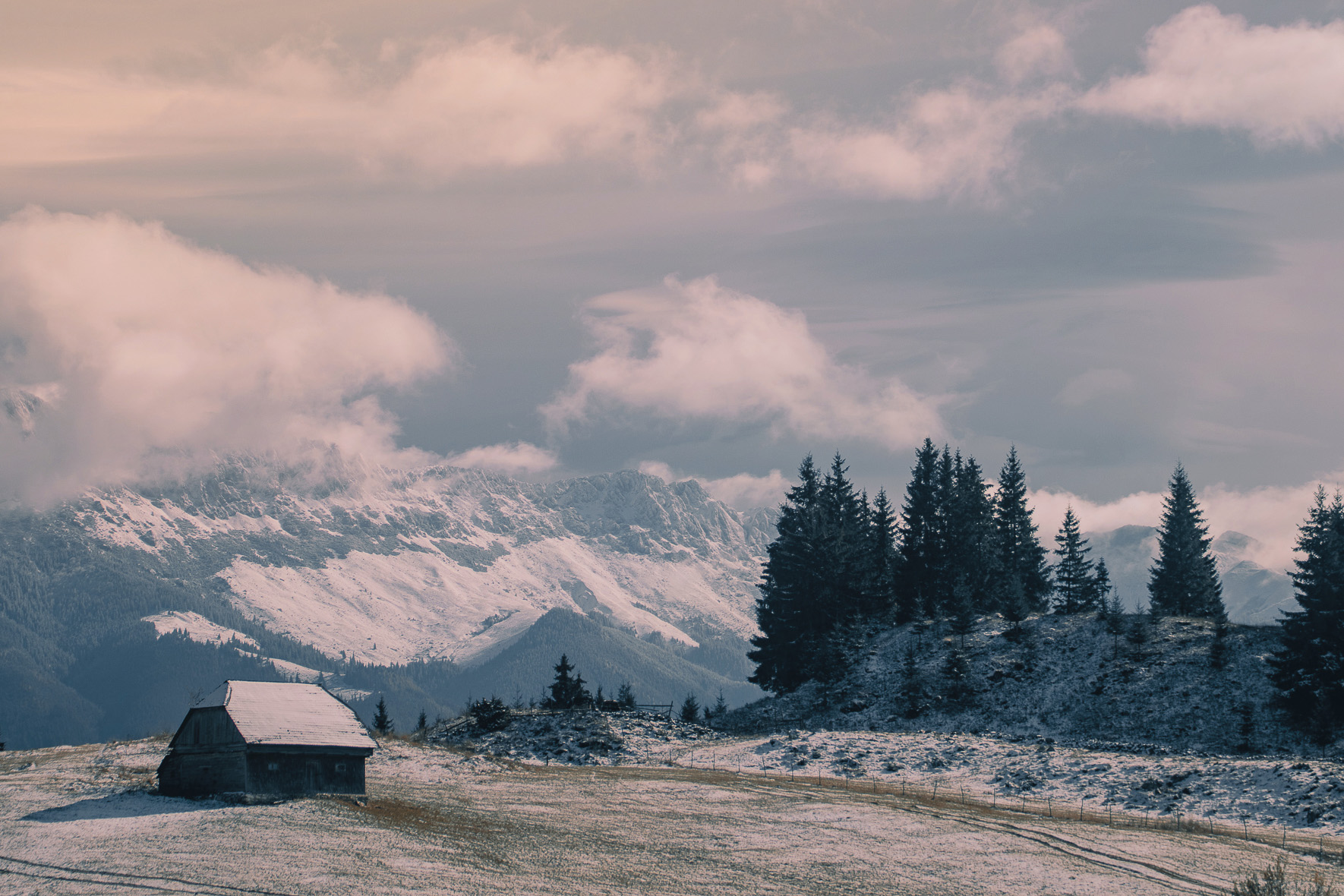 Snow-dusted mountain landscape with a cabin and evergreen trees
